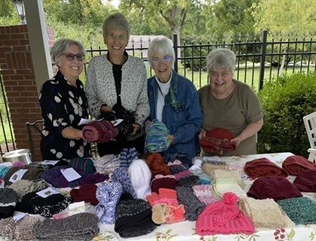 String Theory knitters show off many months’ worth of work—knitted hats and scarves for donation to local nonprofits in winter.