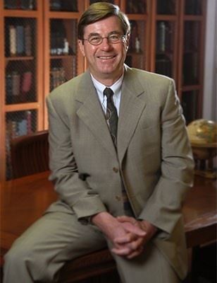 Dr. Craig Brater smiling and sitting on a table.